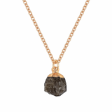 Necklace with a black stone pendant on a gold chain against a white background