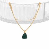Gold necklace with a green pendant on a white background