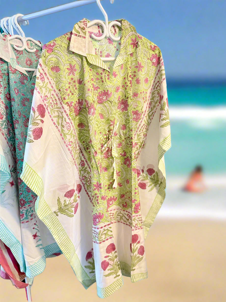 Floral-patterned beach cover-ups on hangers with a beach background