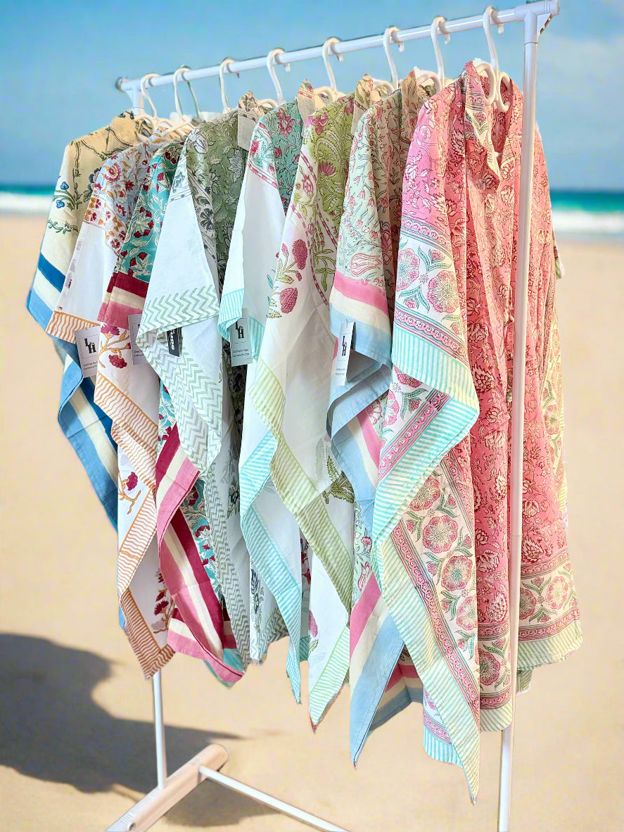 Colorful scarves on a rack against a beach backdrop