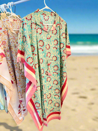 Colorful floral-patterned garment hanging on a rack against a white wall.