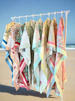 Colorful patterned towels hanging on a rack by the beach