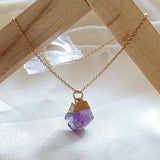 Necklace with a purple crystal pendant on a wooden stand