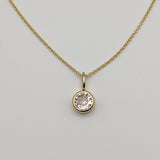 Gold necklace with a diamond pendant on a light gray background