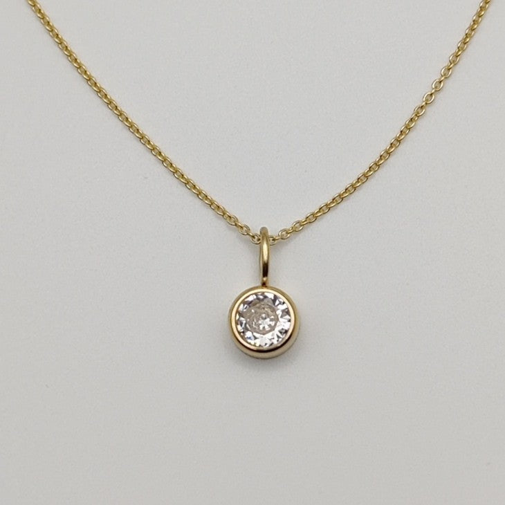 Gold necklace with a diamond pendant on a light gray background