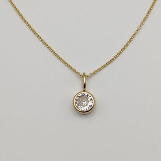 Gold necklace with a diamond pendant on a light gray background