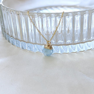 Necklace with a blue pendant on a white surface