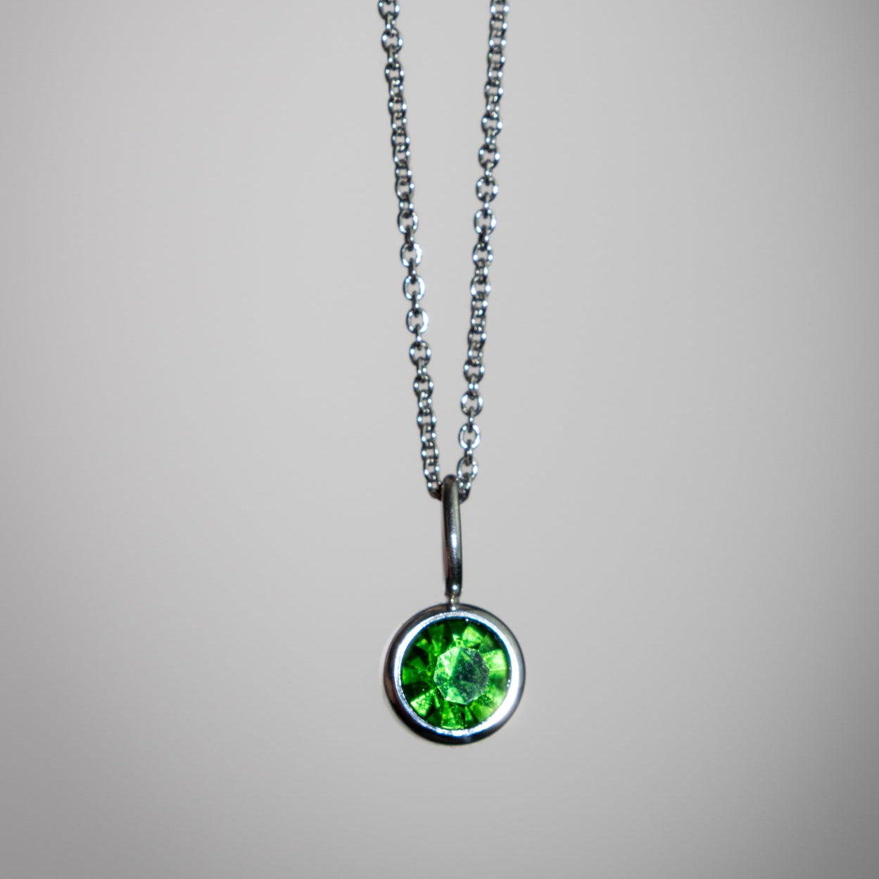 Necklace with a green gemstone pendant on a gray background