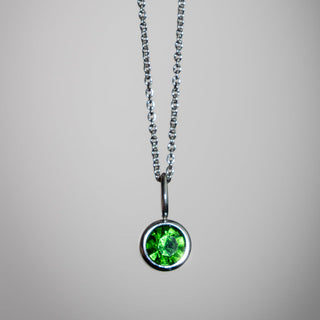 Necklace with a green gemstone pendant on a gray background