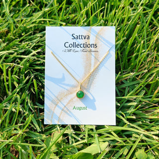 Sattva Collections necklace card with a green gemstone on grass
