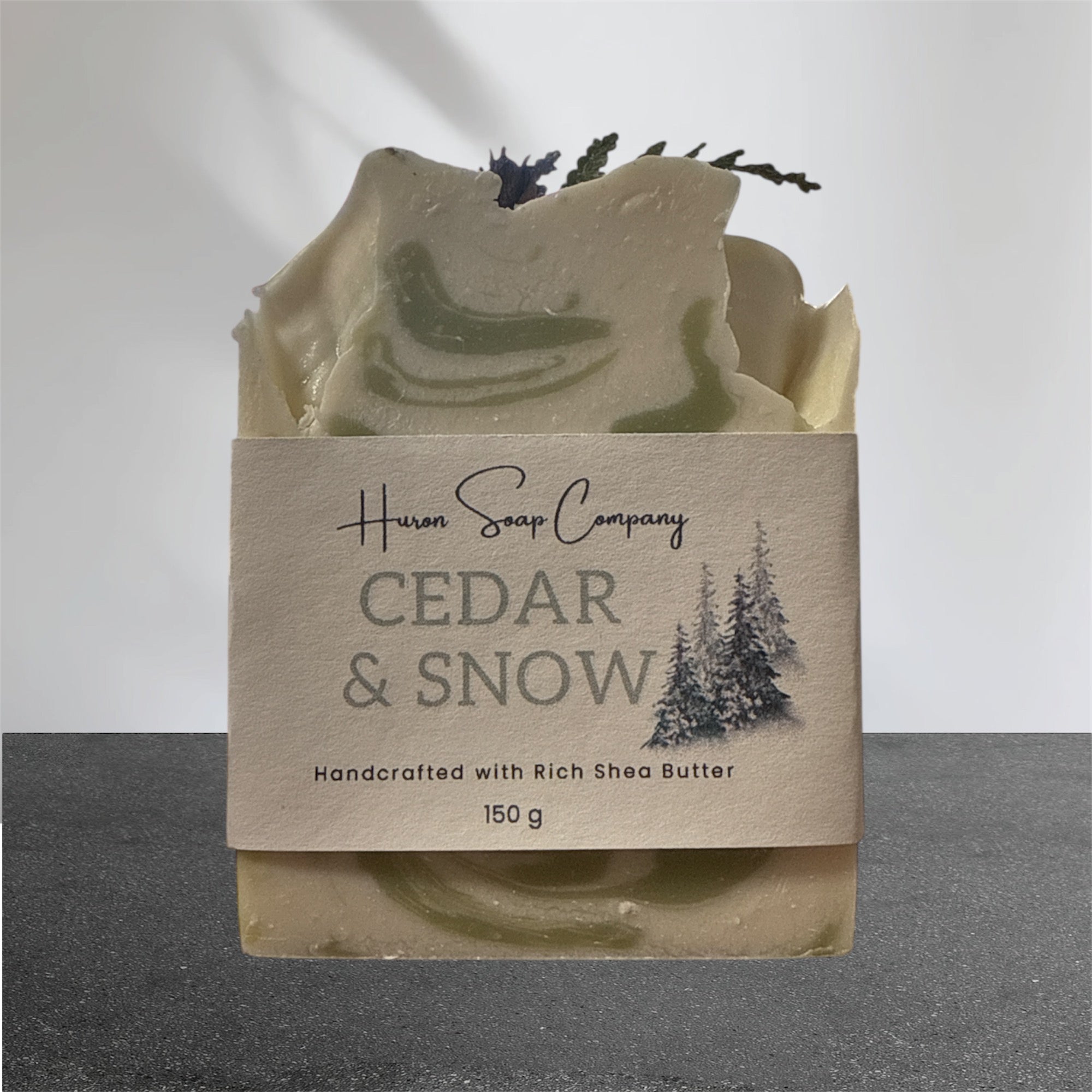 Artisan soap with 'Huron Soap Company Cedar & Snow' packaging on a gray background