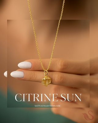 Gold necklace with a citrine sun pendant held by a hand on a brown background