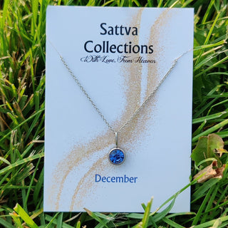 Sattva Collections necklace with blue gemstone on a grass background