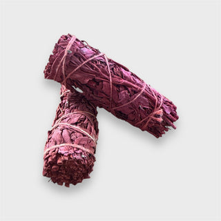 Two bundles of dragon blood white sage tied together on a light gray background