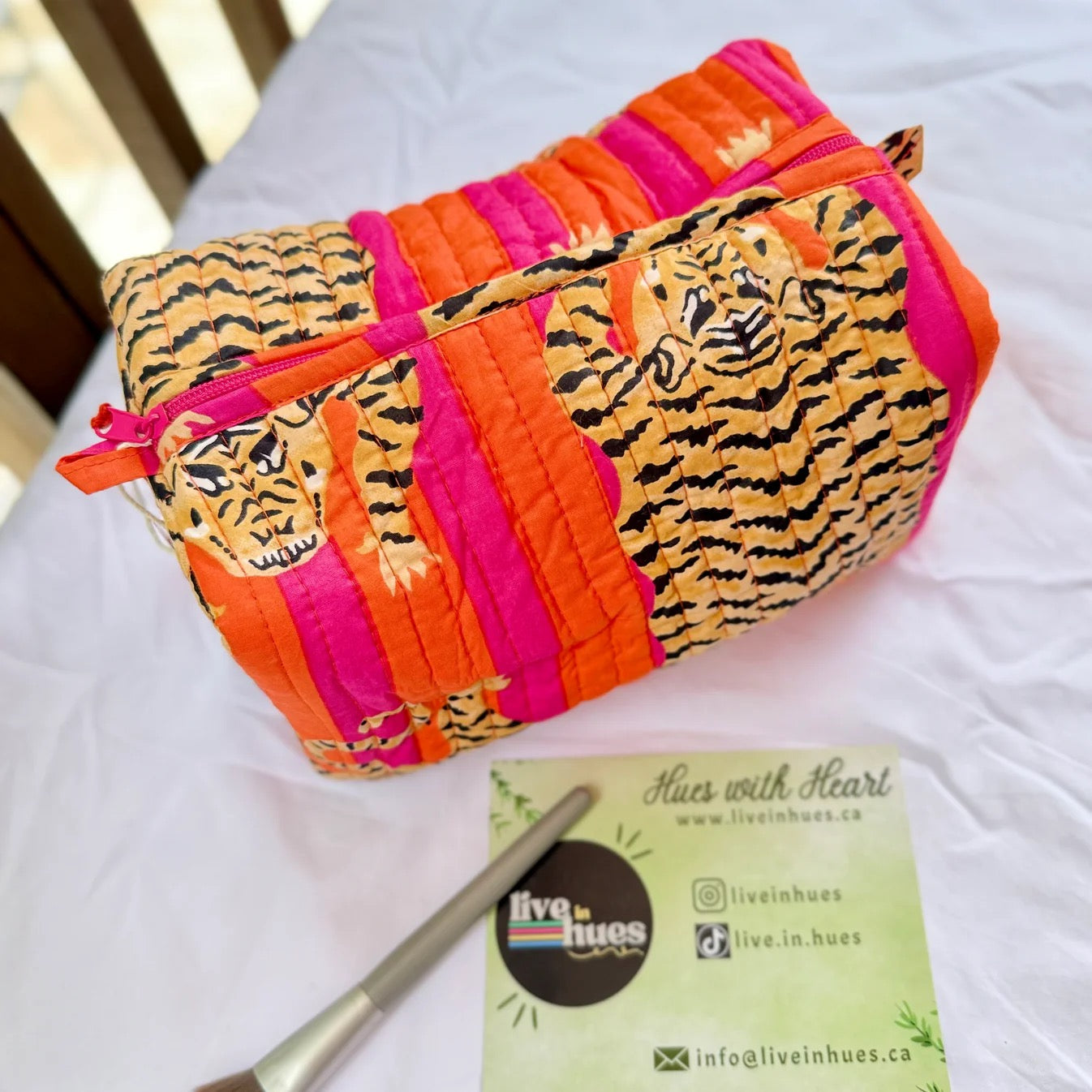 Colorful pouch with tiger design on a white surface, featuring branding text.