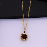 Gold necklace with a red gemstone pendant on a white background
