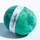 Green bath bomb with a label on a light blue background