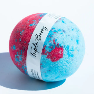 Bath bomb with red and blue speckles and 'Triple Berry' label on a white background