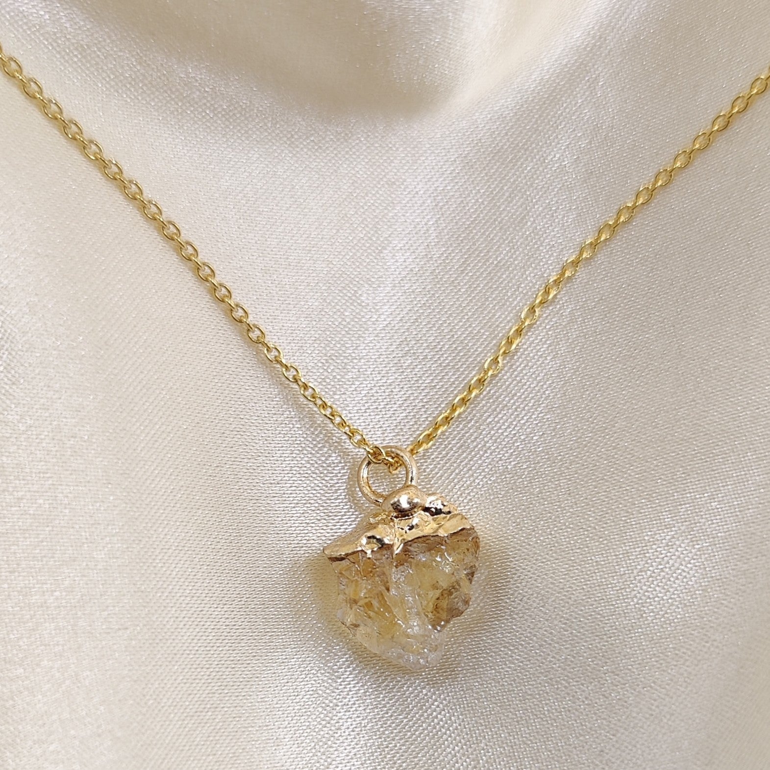 Gold necklace with a pendant on a light fabric background