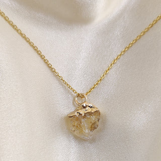 Gold necklace with a pendant on a light fabric background