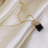 Gold necklace with a black pendant on a white fabric background