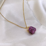Necklace with a purple stone pendant on a white fabric background