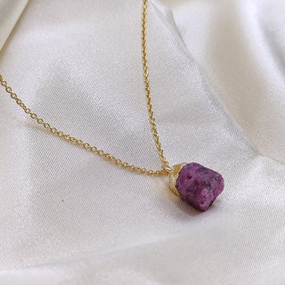 Necklace with a purple stone pendant on a white fabric background