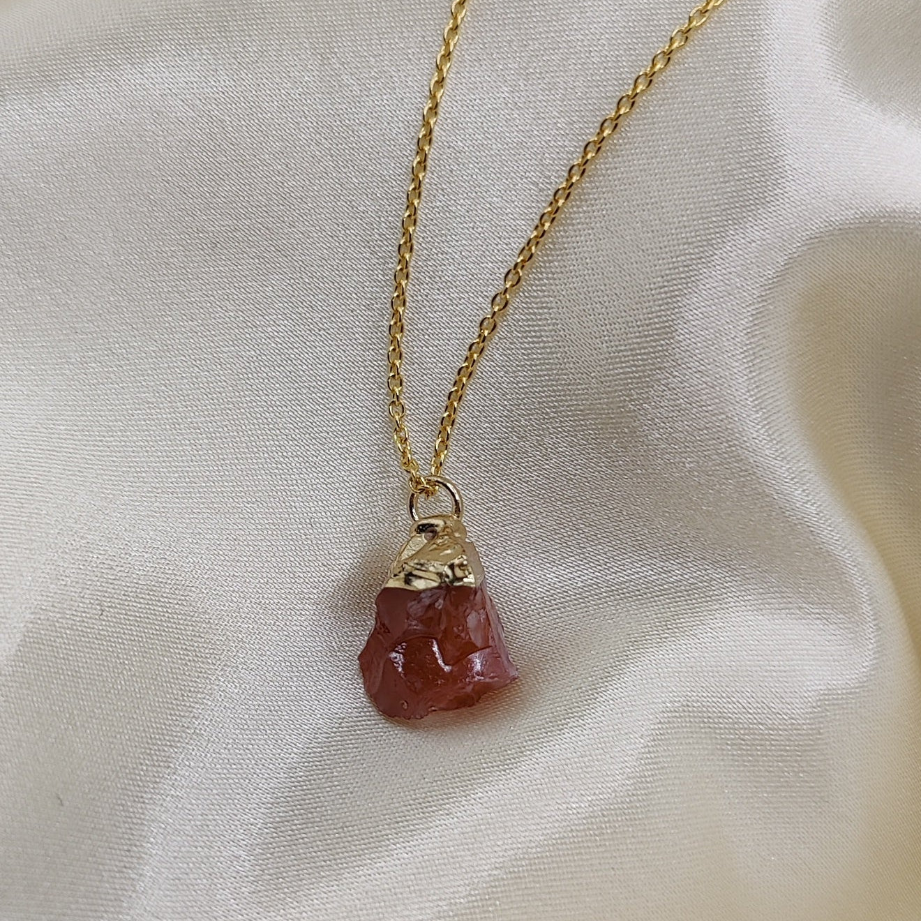 Necklace with a red stone pendant on a light fabric background