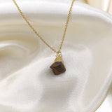 Gold necklace with a triangular pendant on a white fabric background