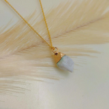 Necklace with a gold chain and stone pendant on a light background