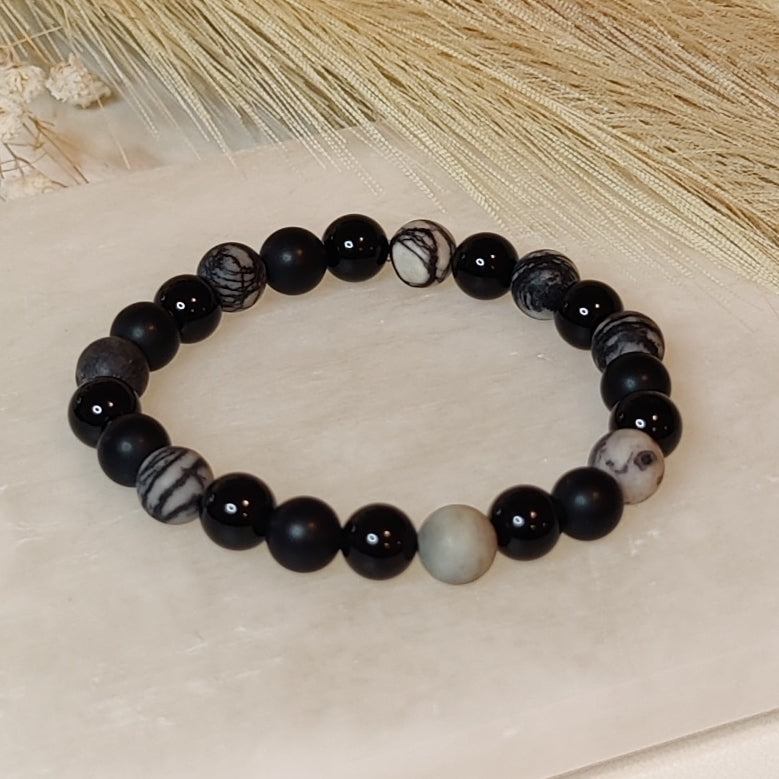 Black and white beaded bracelet on a light stone surface with natural background