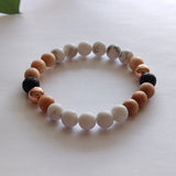 Beaded bracelet with white, brown, and black beads on a light background