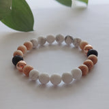 Multicolored beaded bracelet on a light surface with green leaves in the background