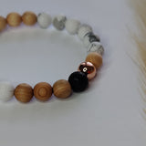 Beaded bracelet with wooden, white, gray, and black beads on a light background
