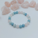 Beaded bracelet with blue and pink beads on a white background with rose quartz stones.
