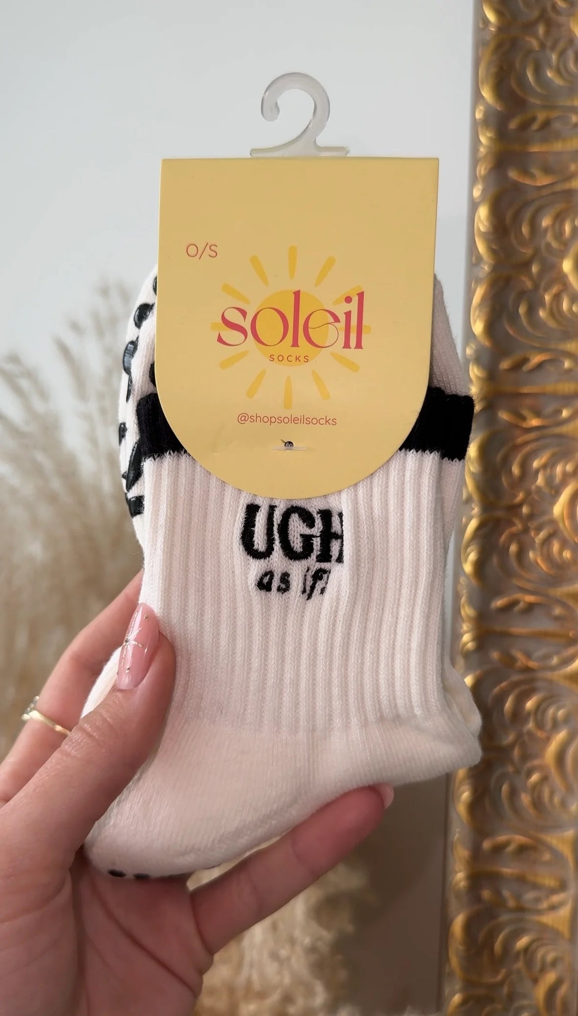 White sock with black text held by a hand against a decorative background