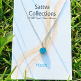 Necklace with blue pendant on a 'Sattva Collections' card in grass