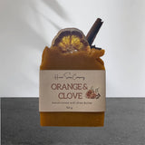 Artisan soap with 'Huron Soap Company Orange & Clove' label on a gray background
