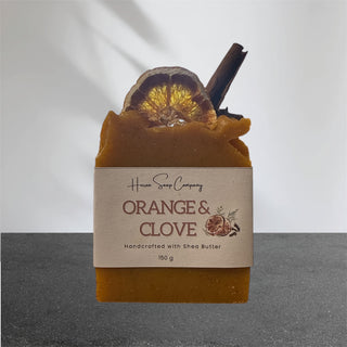 Artisan soap with 'Huron Soap Company Orange & Clove' label on a gray background