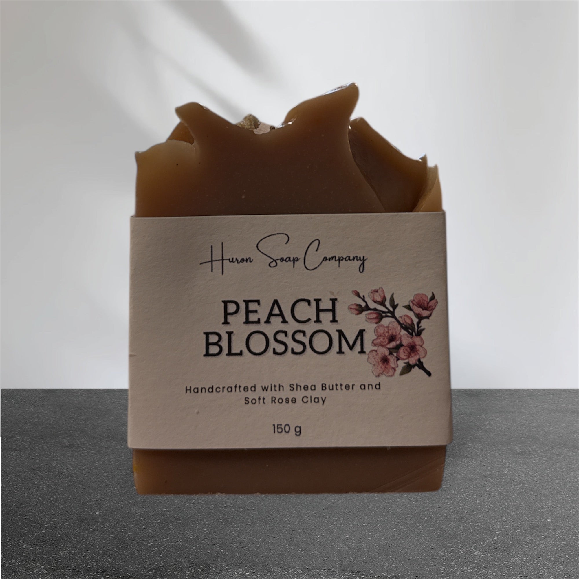 Artisan soap with 'Huron Soap Company Peach Blossom' label on a gray background