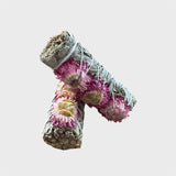 Two rolled white sage smudge sticks with pink sunflowers on a light gray background
