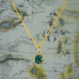 Gold necklace with a green gemstone pendant on a vintage map background