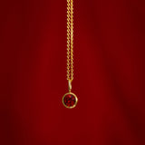 Gold necklace with a red gemstone pendant on a red background