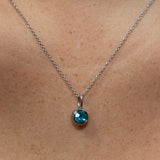 Necklace with a blue gemstone pendant on a person's neck