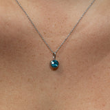 Necklace with a blue gemstone pendant on a person's neck