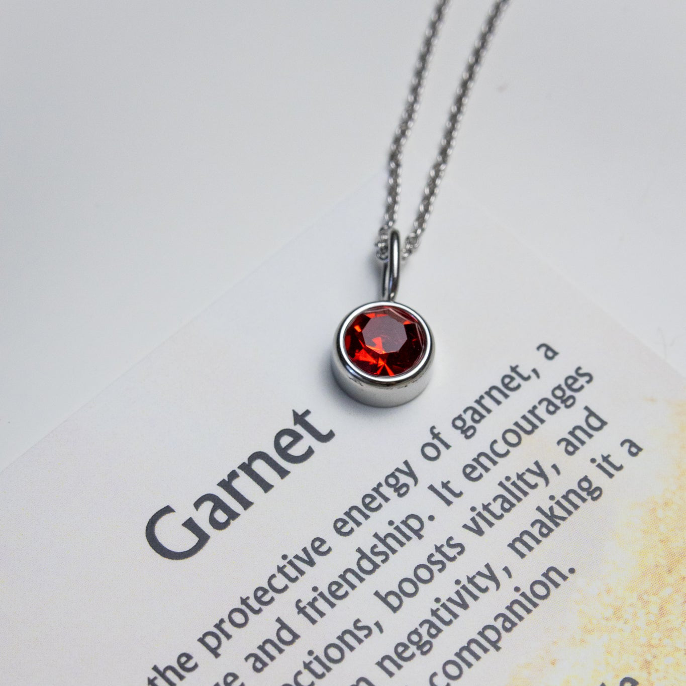 Garnet necklace on a care guide with text about garnet's properties.