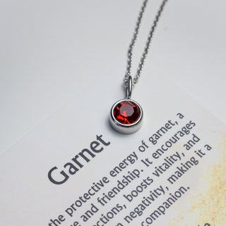 Garnet necklace on a care guide with text about garnet's properties.