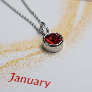 Necklace with a red gemstone pendant on a 'Nativa Collections' card with 'January' text.