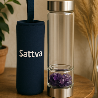 Sattva branded water bottle with a dark blue sleeve and clear body with purple stones on a wooden table.