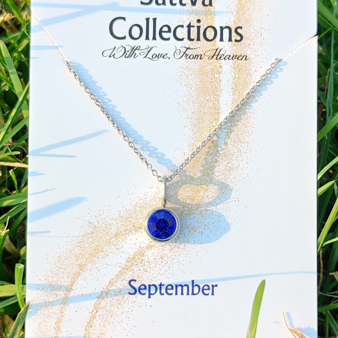 Necklace with a blue pendant on a branded card with grass background